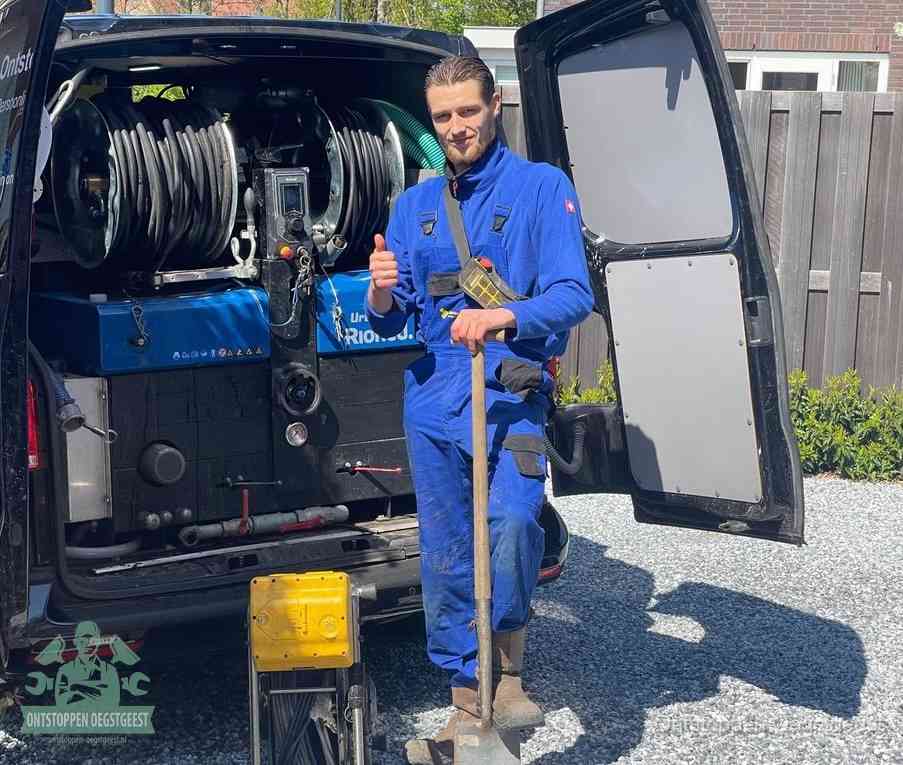 Een tevreden monteur met opgestoken duim naast de bestelbus, slim en snel ingrijpen bespaart geld bij een verstopping in Oegstgeest
